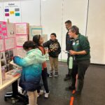 A student presents their project board to a community judge.