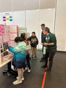 A student presents their project board to a community judge.