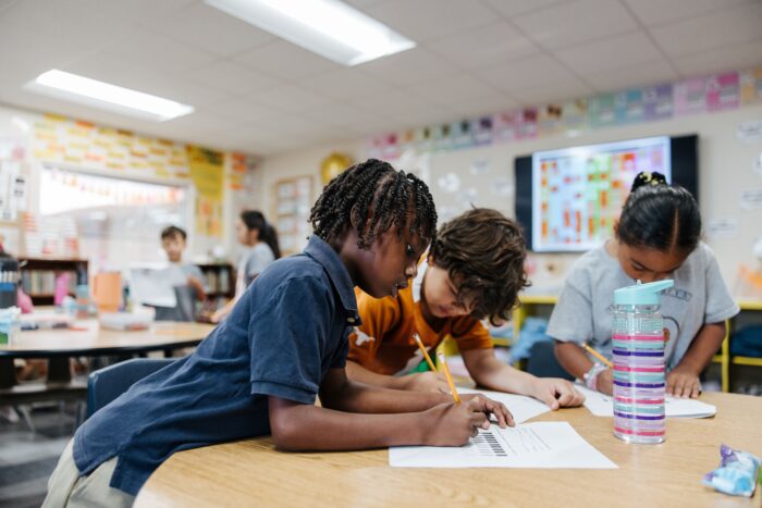 Three students working on worksheets in class