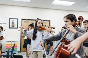 A student watching where she places her fingers on her violin
