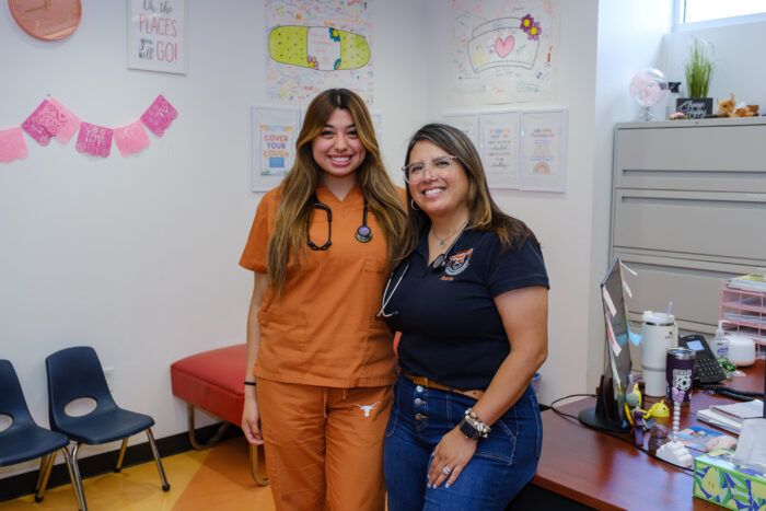 UT Austin Nursing student Daniela Mora in her burnt orange scrubs stands with UT Elementary School Nurse Rachel Ibarra